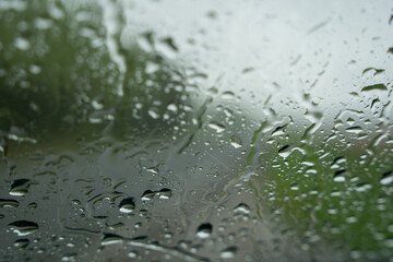a window covered with raindrops forms an interesting pattern and behind them you can see a foggy...