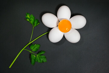 Flower made from chicken eggs and parsley on a dark background. Top view