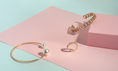 Chain shape and Gold with pearl bracelets and ring on pink and green paper