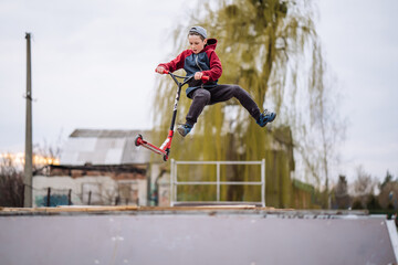 Boy on scooter makes a trick and enjoying his riding in the skate park © onphotoua