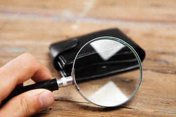 wallet and magnifier on wooden background
