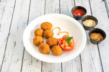 Ration of round croquettes with tomato and various sauces to dip