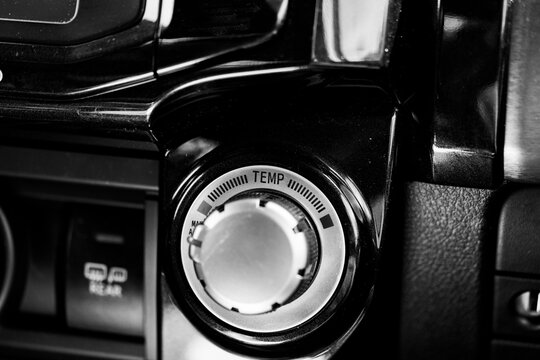 Black and white photo of the Temp, or temperature, knob in a vehicle. This knob controls the heat or air conditioning. Concepts of comfort, climate control, road trip.