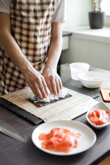 Obraz na płótnie Canvas Young teenage boy making maki sushi at home