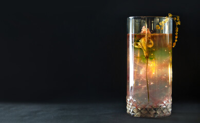 Cocktail made of natural ingredients on a black background. Composition of fresh flowers in a glass, concept