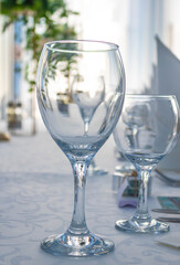 Luxuriously set table with empty bluish wine glasses with flowers and napkins in the background against the light