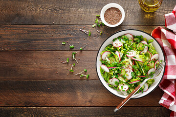 Radish and cucumber salad with fresh green onion in bowl, Top view