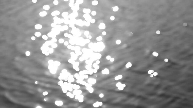 Beautiful sparkling shiny texture of blurry blue river water with sun reflected on surface of water. 4k abstract stock video black and white bokeh background filtered in vintage retro style