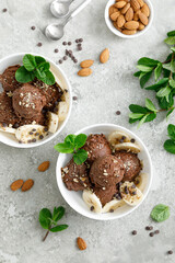 Chocolate and banana fruit ice cream with almond nuts served in bowls, top view