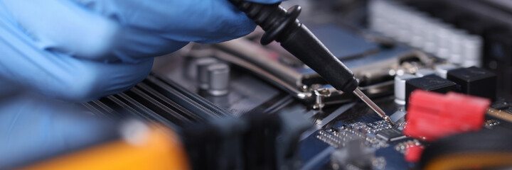 Gloved technician with tester checks motherboard closeup