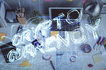 Blockchain theme hologram drawings over computer on the desktop background. Top view. Multi exposure. Concept of cryptoeconomy.