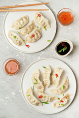 Jiaozi gyoza dumplings steamed on white plates with soy sauce and chili sauce. Food takeaway, home delivery