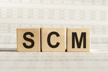 SCM abbreviation - Supply Chain Management, on wooden cubes on a light background.