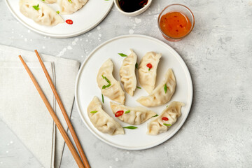 Jiaozi gyoza dumplings steamed on white plates with soy sauce and chili sauce. Food takeaway, home delivery