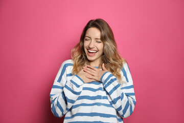 Fototapeta premium Cheerful young woman laughing on pink background