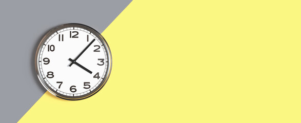 Plain wall clock in the center of grey and yellow background. Four o'clock. Close up banner with copy space, time management or school concept and lunch time. Opening or closing hours. Schedule