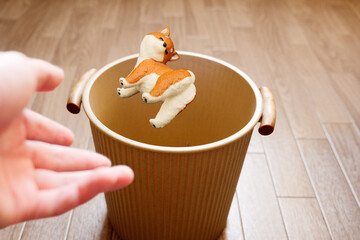 犬のペットのミニチュアをゴミ箱へ投げ捨てる
