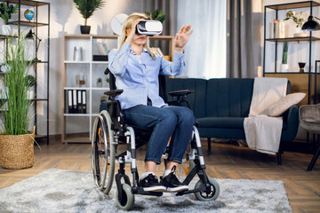 Fototapeta na wymiar Young woman in wheelchair wearing 3d glasses for enjoying virtual game. Modern innovative technology for disabled people. Rehabilitation concept.