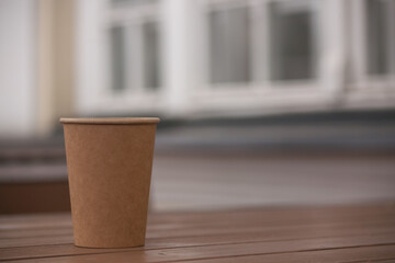 eco paper cup with coffee or tea, on a wooden table. Breakfast outside, in the park, on a bench 