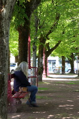 Fototapeta na wymiar Woman sitting on bench in town square.