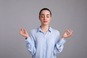 Young woman meditating on light grey background. Personality concept - obrazy, fototapety, plakaty