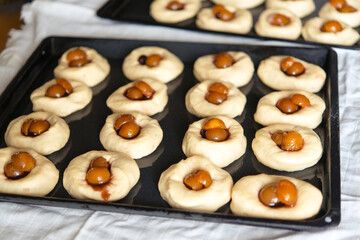 Stages of cooking yeast buns with jam and fruit. Stage 3 - adding fruit. A series of photographs. Handmade homemade baking.