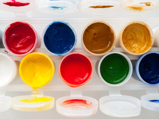 jars with paints of different colors, top view, close-up, development of artistic skills in children, drawing, hobbies, drawing with a brush