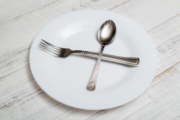 The spoon and fork are on an empty plate. Diet concept, intermittent fasting.