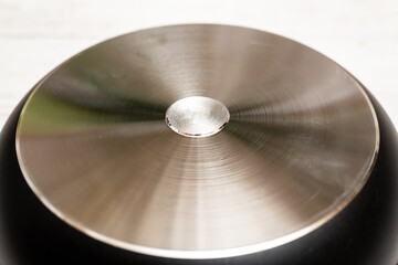 Bottom, back side of a new aluminum frying pan on a white wooden background.