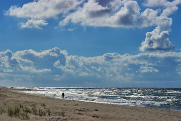 A man walks along the coast of the sea against the backdrop of waves