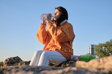 The girl drinks water from a bottle. Lunch in nature. Travel outside the city al