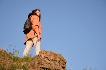 The girl climbs a rocky mountain. Travel outside the city alone.