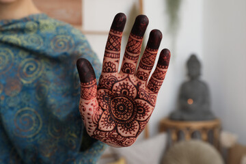 Woman with henna tattoo on palm indoors, closeup. Traditional mehndi ornament