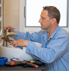 Plumber repairs bathroom faucet