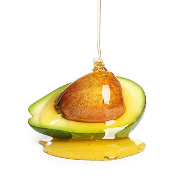 Pouring essential oil onto cut avocado on white background