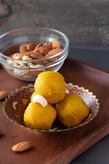 Famous authentic Indian sweets Laddu made from besan or chickpeas flour. Vegetarian and healthy food.  Wooden plate background. Selective focus.