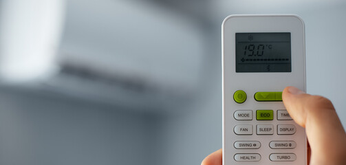Close-up of male hand using remote control of air conditioner. Panoramic banner view.