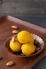 Famous authentic Indian sweets Laddu made from besan or chickpeas flour. Vegetarian and healthy food.  Wooden background. Selective focus.