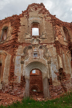 The entrance to the abandoned ruined old church is made of brick with crumbling plaster. Outside view. Russia, Smolensk region, 1753.