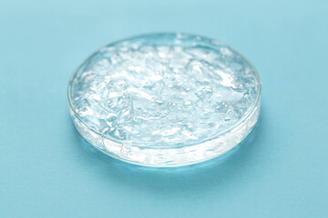 Transparent cosmetic gel in glass petri dish on blue background. Concept laboratory tests and research, making cosmetic.