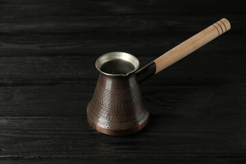 Copper turkish coffee pot on black wooden table