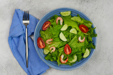 fresh summer salad of vegetables lettuce leaves, cherry tomatoes, cucumber slices and shrimp, seafood dish