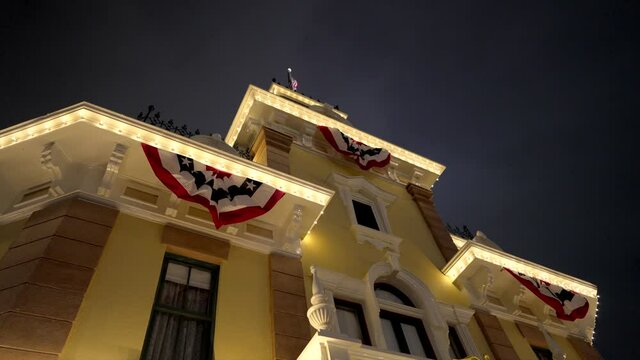 This video shows an old time town hall type building lined with patriotic American flag banners and bunting swags blowing in the wind.