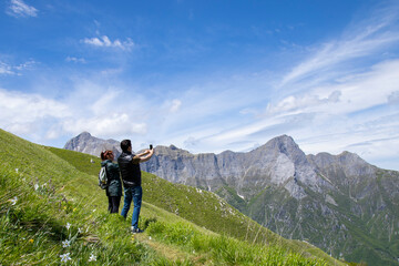 Fototapeta na wymiar man and woman make photo with phone in flowered mountains of Apuan Alps