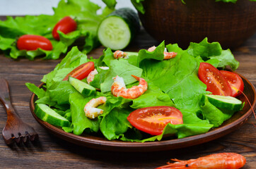fresh summer salad of vegetables lettuce leaves, cherry tomatoes, cucumber slices and shrimp, seafood dish isolated on a white background