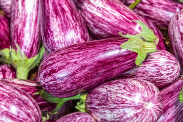 Purple striped eggplants in a wicker basket on a store shelf. Fresh vegetables at the grocery...