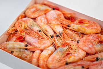 Frozen shrimps in a white carton packaging. Dry freezing of seafood delicacies