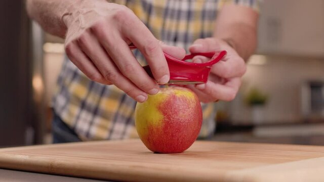 Slicing An Apple With A Wedge Slicer. Male Uses A Red Apple Slicer To Cut An Apple Into Wedges Close Up