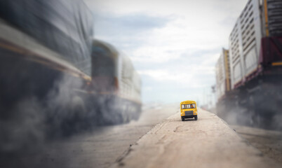 Yellow school bus toy model on country road with blurry truck.Back to school,education and transpotation concept background.