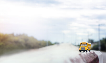 Yellow school bus toy model on country road.Back to school,.education and transpotation concept background.